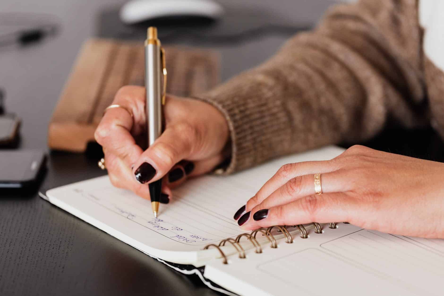 crop woman writing down notes in diary dissertation writing