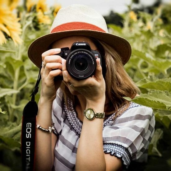 selective focus photography of woman holding dslr camera