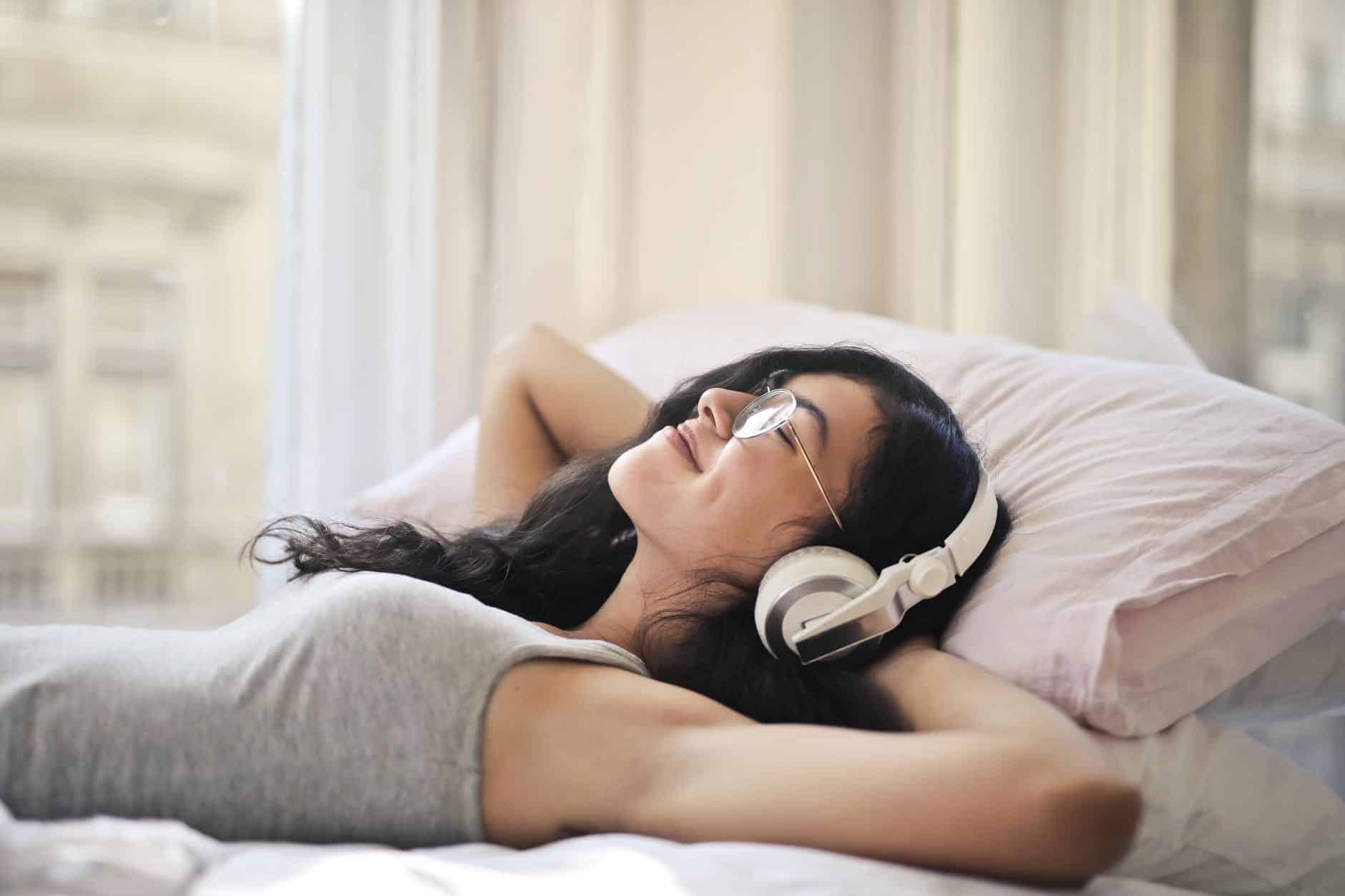 woman in gray tank top lying on bed relaxing to improve productivity