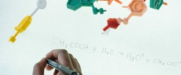 crop ethnic clever student writing formula after analysis of molecule model in university