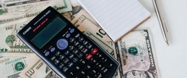 calculator and notepad placed on usa dollars stack