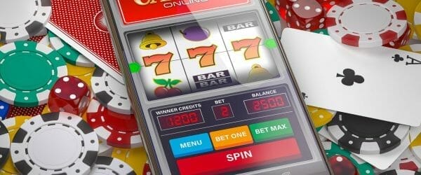 Online casino. Slot machine on smartphone screen, dice, casino chips and cards.