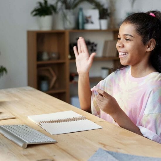 woman in pink shirt sitting by the table while smiling