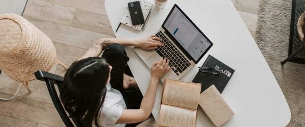 young lady typing on keyboard of laptop in living room