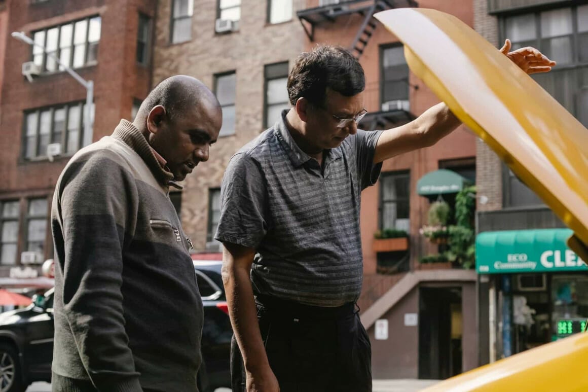 serious ethnic men checking engine of car after car accident