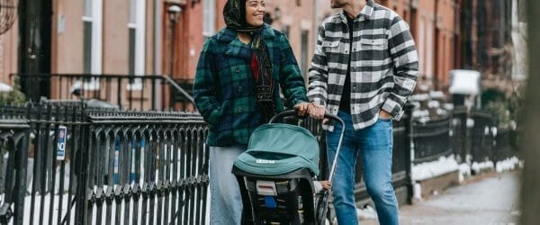 happy multiethnic parents walking with baby stroller