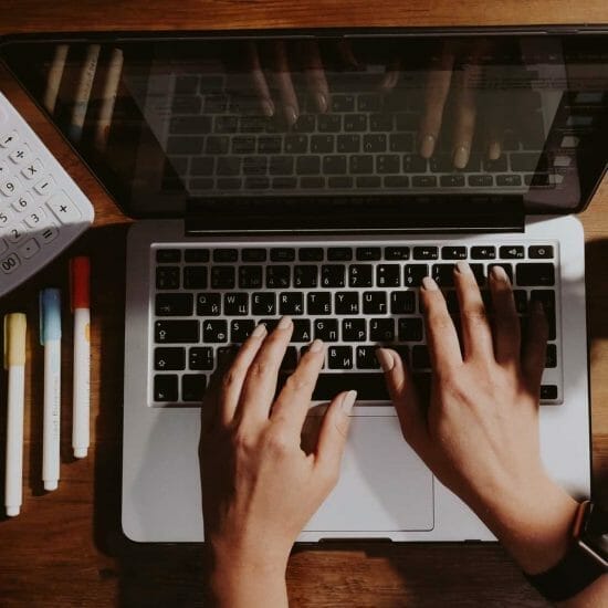 person using macbook pro on brown wooden table