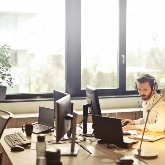 man with headphones facing computer monitor