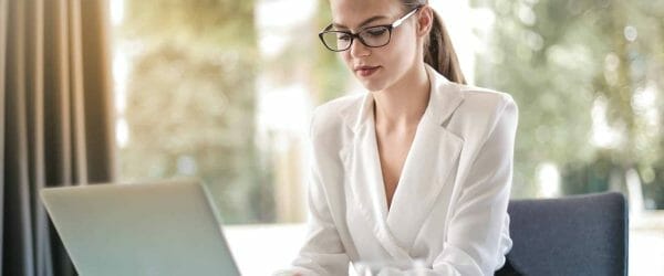 concentrated female entrepreneur typing on laptop in workplace