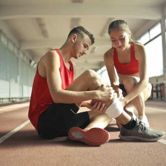 woman wrapping man s leg with bandage