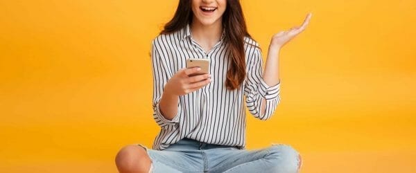 portrait excited young girl holding mobile phone