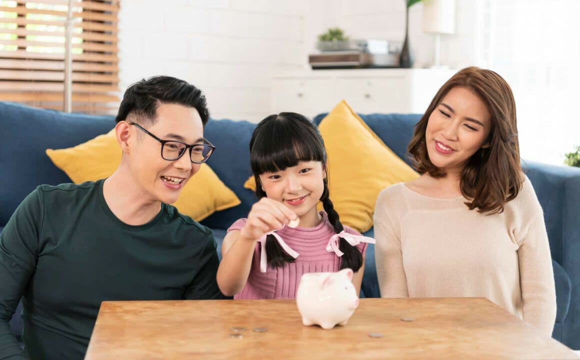 Asian Family Putting Money in Piggy Bank – Family Budget