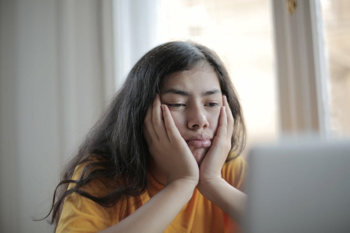 melancholic woman watching video on laptop at home showing procrastination