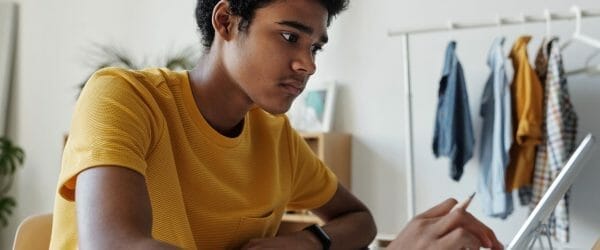 man in yellow crew neck t shirt while using tablet