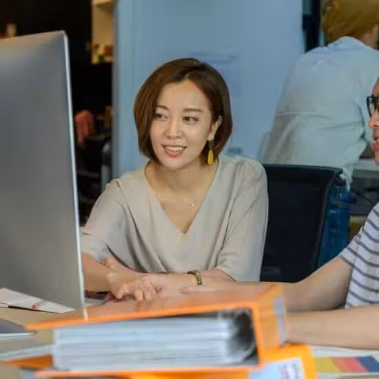 man and woman sitting while looking at the computer monitor