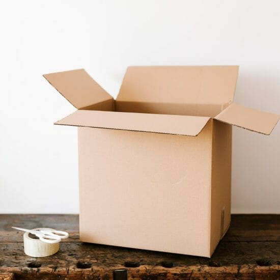 cardboard box on dark wooden table near tape and scissors