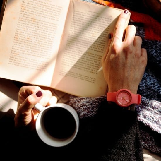 person reading book and holding coffee