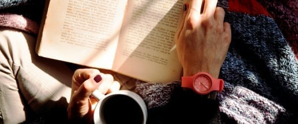 person reading book and holding coffee