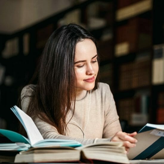 brunette woman reading book table with lamp