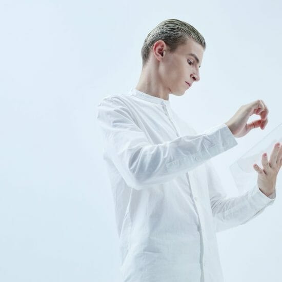 a low angle shot of a man in white long sleeves holding a clear glass