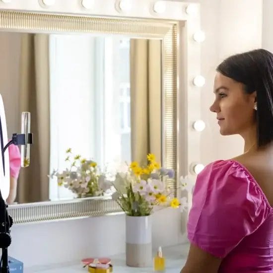 a woman video recording herself using a cellphone on a ring light