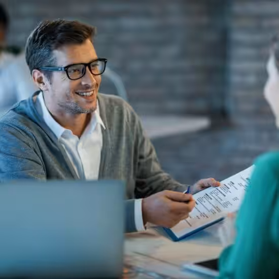 happy-businessman-talking-to-his-colleague-while-going-through-financial-reports